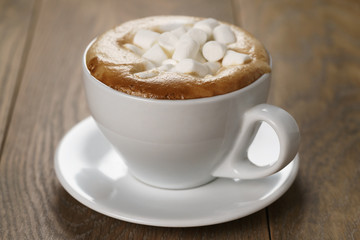 cup of cappuccino with marshmallow on wooden table, shallow focus