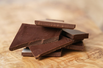 stacked pieces of chocolate bar on wooden table, shallow focus