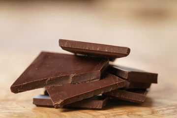 stacked pieces of chocolate bar on wooden table, shallow focus