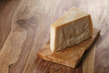 piece of italian parmesan cheese on wooden cutting board, simple rustic photo