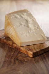 closeup of piece of italian parmesan cheese on wooden cutting board, simple rustic photo