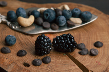 Bramble close up, selective focus. Spatula for cake with nuts, chocolate and berries on the wooden background.