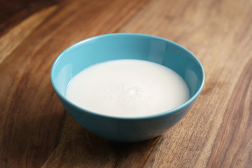 fresh milk in the blue bowl on wood table, organic food