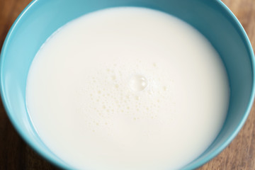 fresh milk in the blue bowl on wood table, organic food