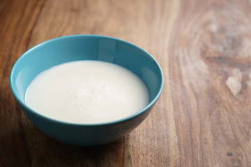 fresh milk in the blue bowl on wood table with copy space, organic food