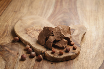 chunks of gianduja with hazelnuts on wood board, premium chocolate dessert