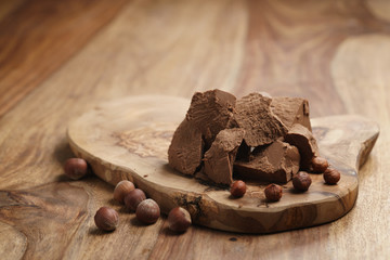 chunks of gianduja with hazelnuts on wood board, premium chocolate dessert