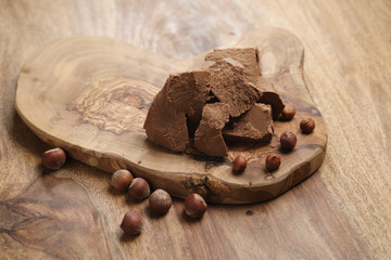 chunks of gianduja with hazelnuts on wood board, premium chocolate dessert