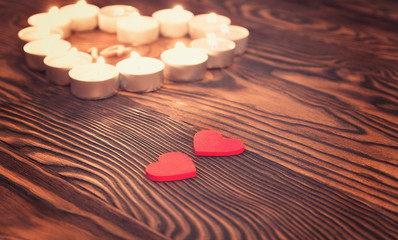 Two hearts, burning candles on wooden. Valentine's Day.