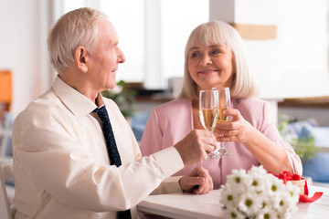 Two lovely elderly people holding up glasses of champagne