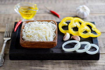 Pickled cabbage and pepper in a wooden bowl on the table