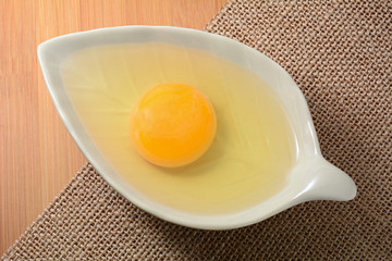 egg yolk in bowl and on wooden table