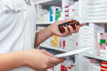 
Woman pharmacist holding prescription checking medicine in pharmacy - drugstore.