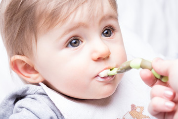 infant girl fed by her mother's hand