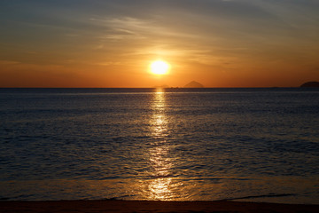 Sunrise over the sea. Mountains on the horizon