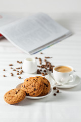 Oatmeal cookies, coffee grains and cup of hot coffee on white table