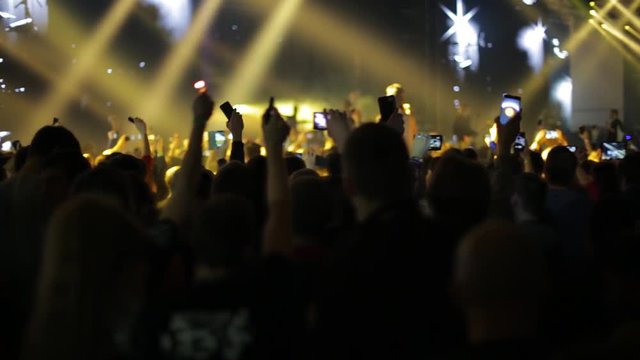 People waving hands and phones at rock concert