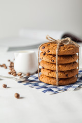 Oatmeal cookies, coffee grains and cup of hot coffee on white table