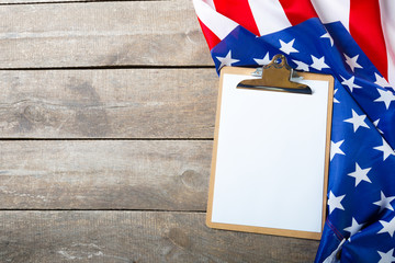 blank clip board and USA flag on wooden background