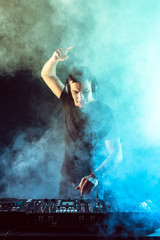 DJ mixing music on mixer on dark background
