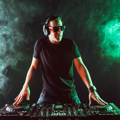DJ mixing music on mixer on dark background