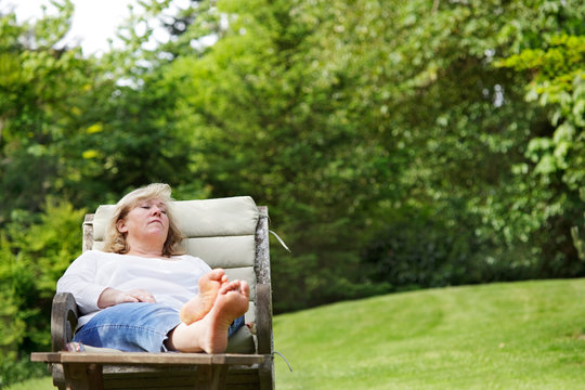 Mature woman dozing with her feet up in a garden chair