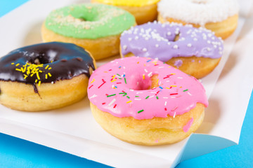 Naklejka na ściany i meble Strawberry, chocklate and other donuts in paper box on blue background