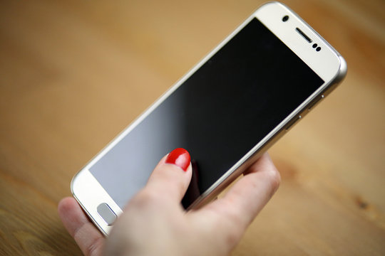 Smartphone tactile avec main d'une jeune femme vernis rouge sexy sur son téléphone portable