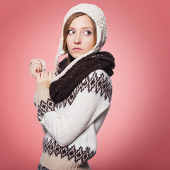 Cut young woman in winter outfit all in snow on a isolated pink background