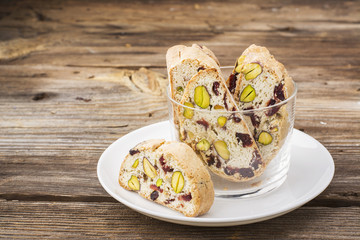 Crispy traditional delicious Italian biscotti cookies or kantuchchi with pistachios and dried cranberries in a glass on  marble background. selective focus