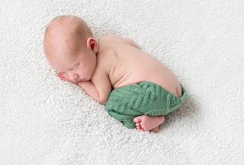 sweet sleeping baby on white blanket in green panties
