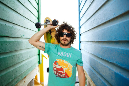 Portrait of a young guy with beard and  a long board skateboard