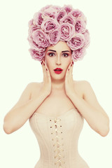 Vintage style portrait of young beautiful slim woman in corset with fancy roses wig on her head and shocked expression 