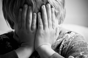 Small boy resting his head in his hand crying 