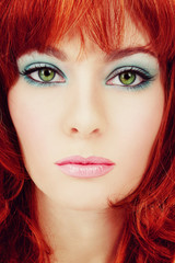 Vintage style close-up portrait of young beautiful green-eyed girl with red hair and stylish makeup