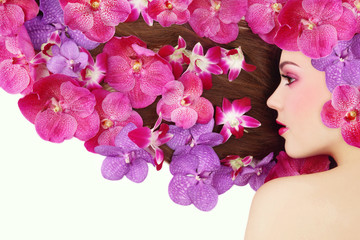 Vintage style profile portrait of young beautiful girl with bright make-up and colorful orchids in her long hair