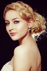 Vintage style portrait of young beautiful blond woman with fancy prom hairdo and smoky eyes make-up