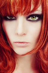 Fototapeta premium Vintage style close-up portrait of young beautiful red-haired green-eyed girl with smoky eyes make-up