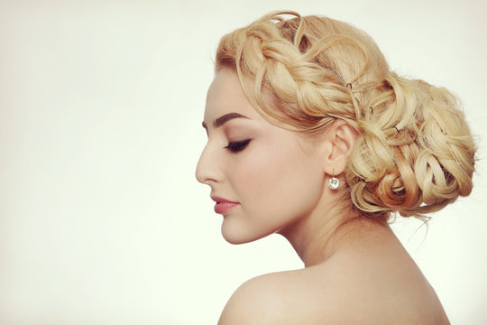 Vintage style profile portrait of young beautiful blond woman with fancy prom hairdo