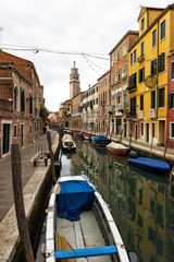 Fototapeta na wymiar Typical Venice canal with moored boats and colorful buildings
