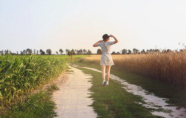 young woman walking along the road in the sunset field. vintage lifestyle background. - 132459586