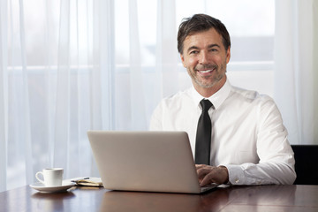  Businessman teleworking at home. On a Laptop. Smiling