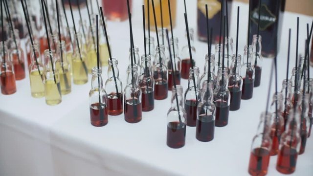 Group of colorful little bottles. Alcoholic cocktails, liqueurs on the white table with cocktail sticks.