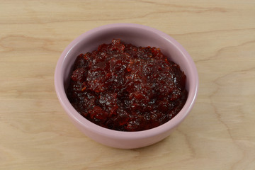 Pepper jam in pink condiment dish on wooden table