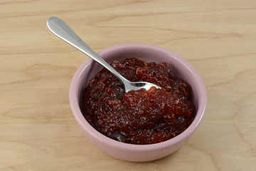 Pepper jam in pink condiment dish with spoon