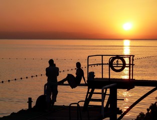 At sunrise. Summer. Romantic date on the beach. Memory photo in backlighting against the sea and...