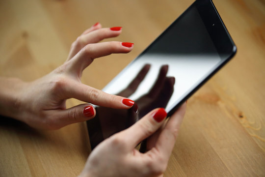Tablette tactile avec main d'une jeune femme vernis rouge sexy qui utilise une application