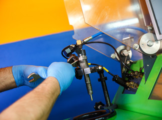 Professional mechanic testing diesel injector in his workshop.