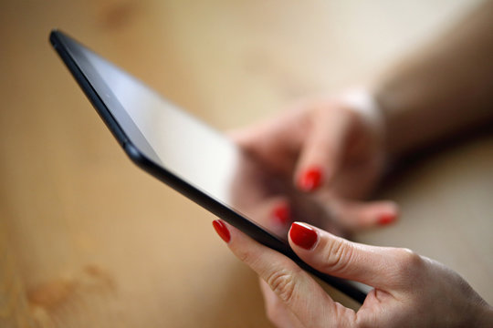 Tablette tactile avec main d'une jeune femme étudiante en vernis rouge qui utilise une application (menu de restaurant)