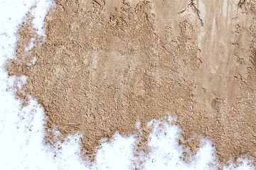 Texture of sand on which snow, background sand and snow in the street